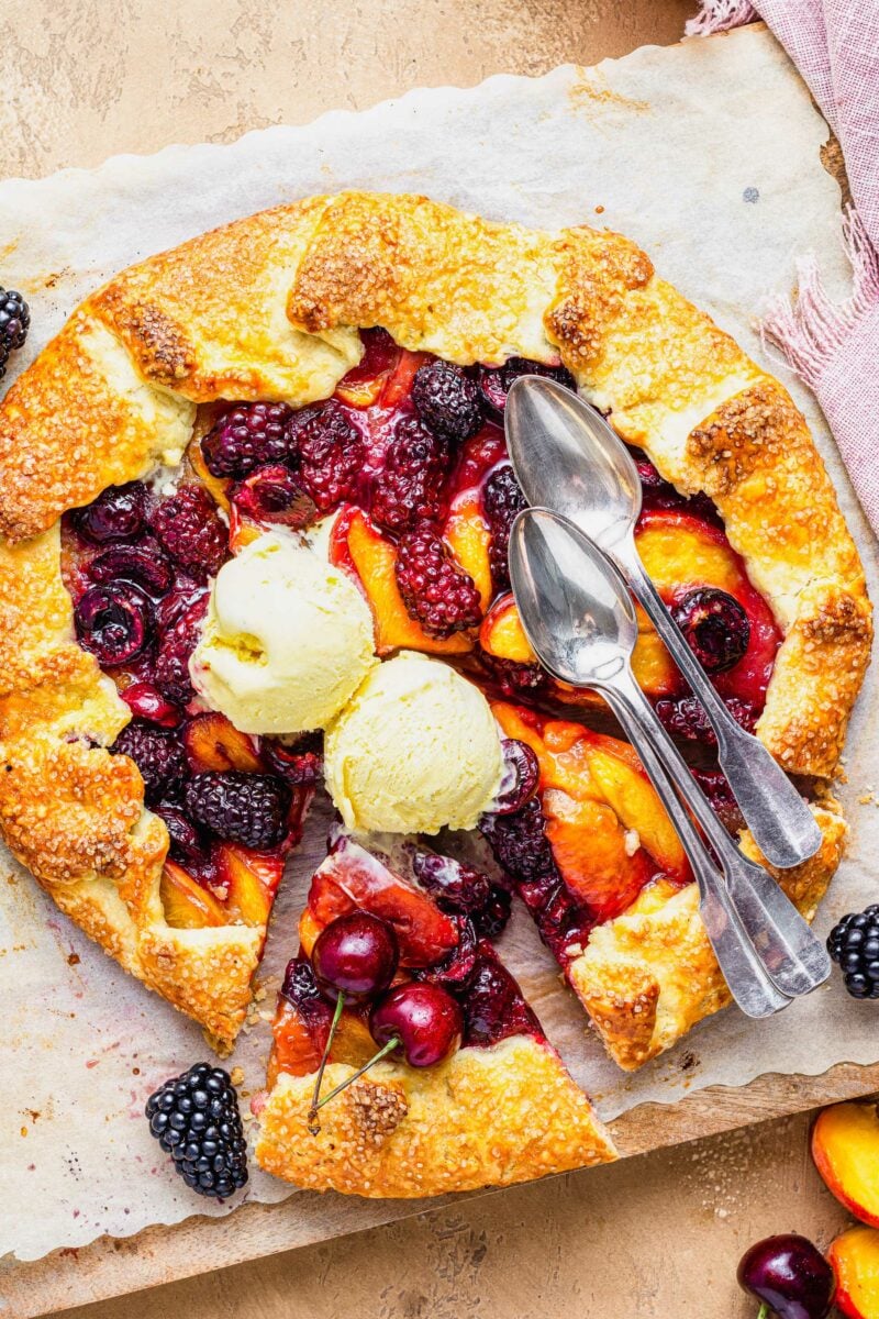Two spoons and two dollops of vanilla ice cream are placed atop the galette. 