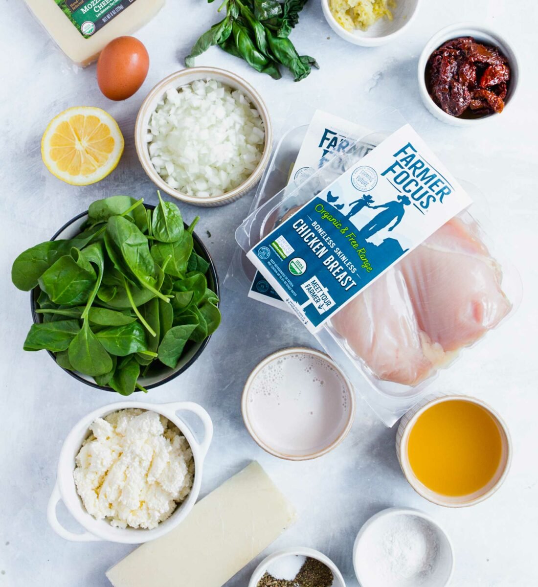The ingredients for stuffed chicken breasts are placed on a white surface.