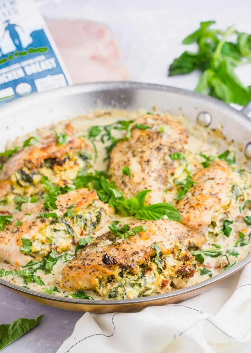 A skillet is filled with stuffed chicken breasts and sauce.