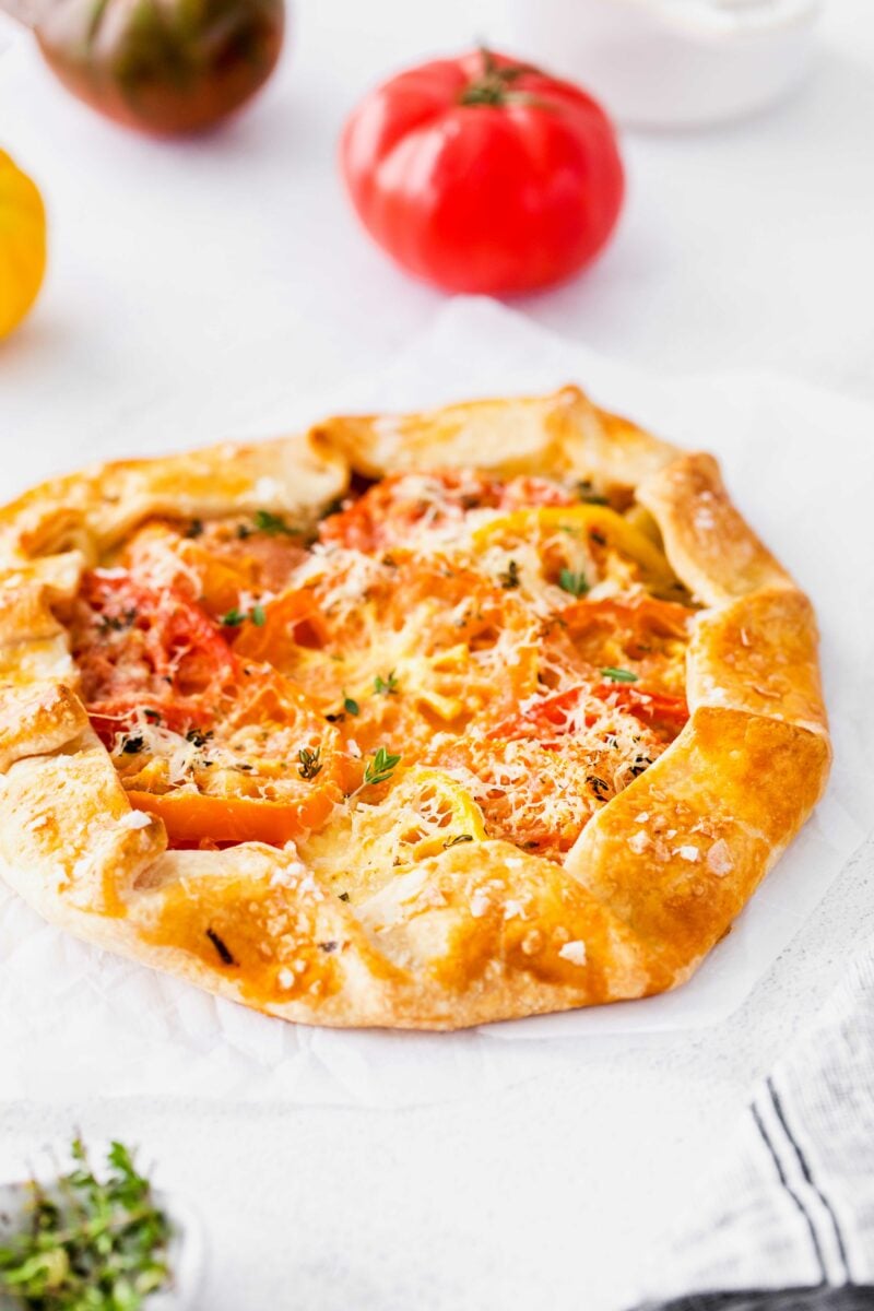A freshly baked tomato galette is presented on a white surface. 