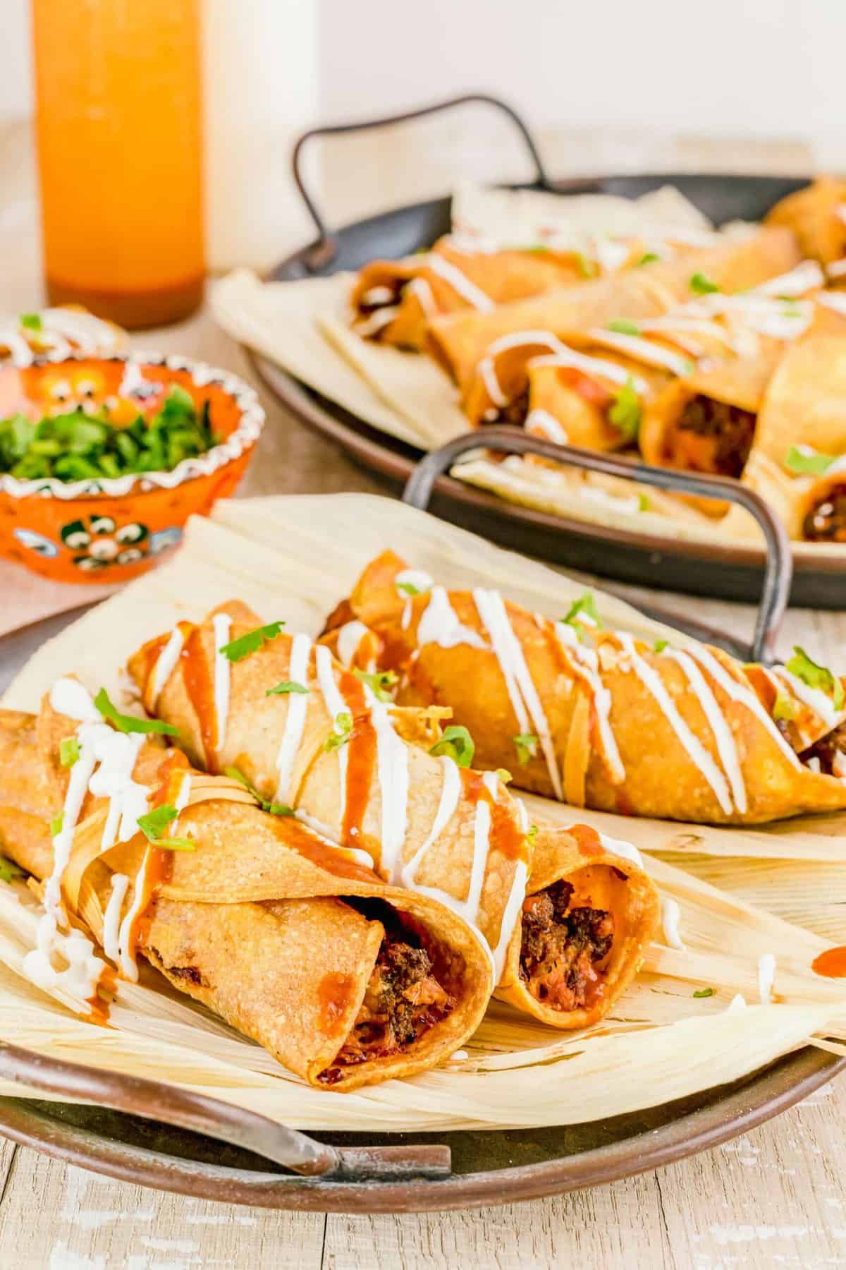 Taquitos are drizzled with sour cream and red sauce.