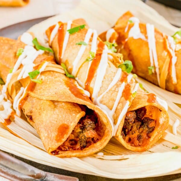 Several air fried taquitos are placed on corn husks.