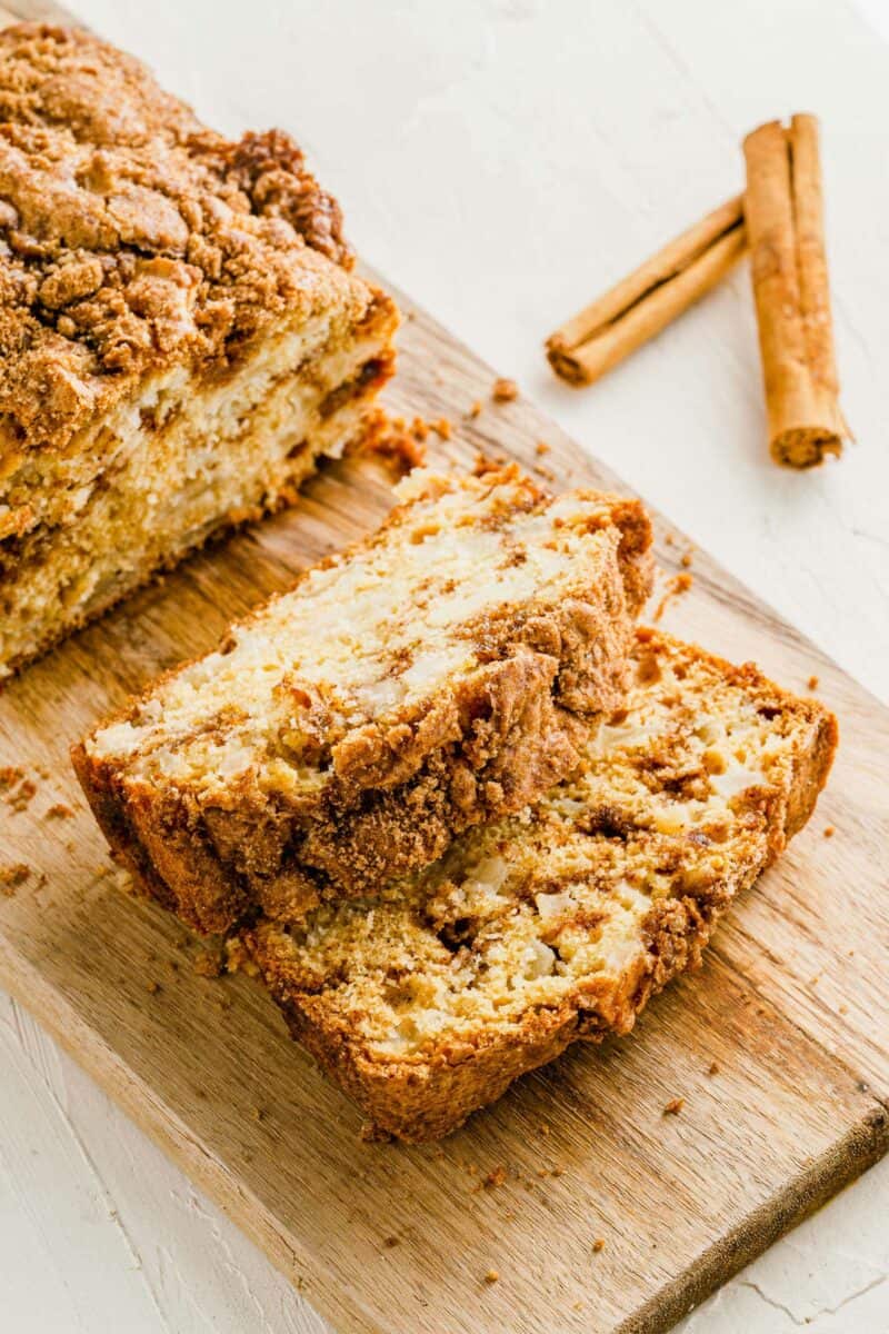 Slices of cinnamon apple bread are on a wooden cutting board. 