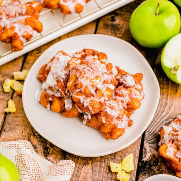 Several glazed fritters are placed on a white plate.