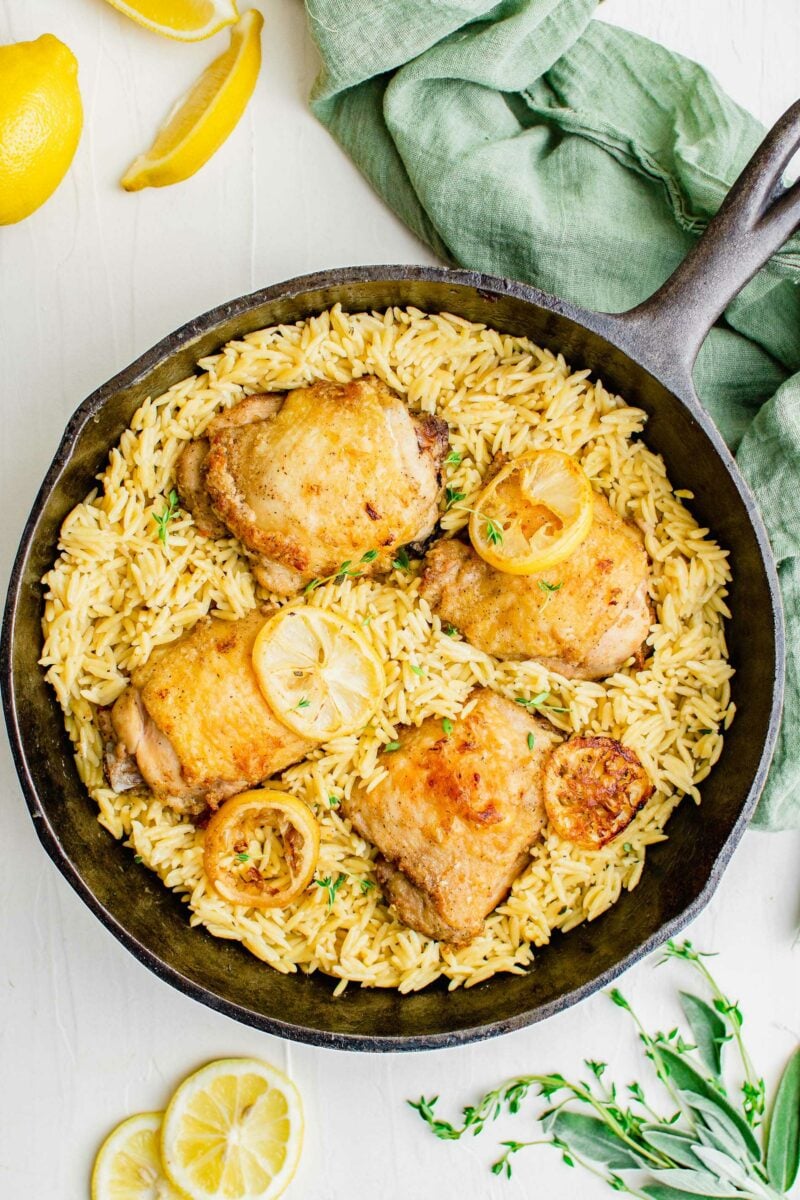 A dutch oven is filled with orzo and chicken. 