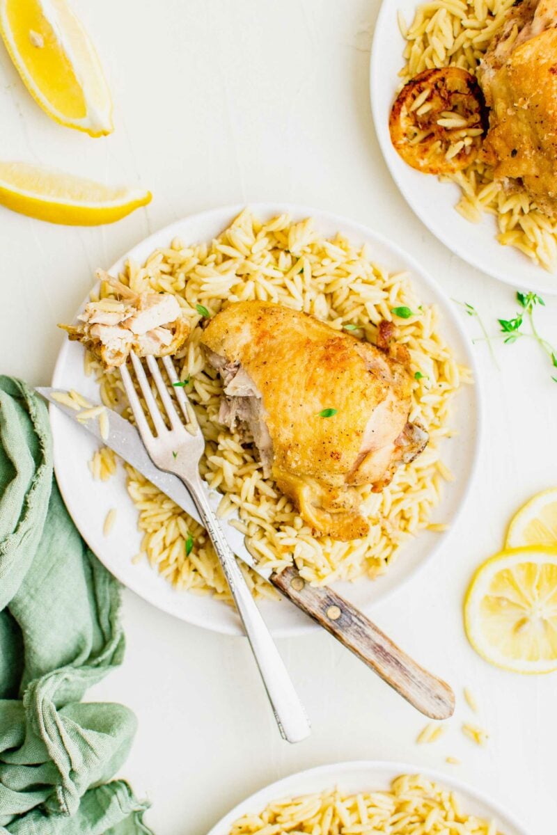 A fork and knife are placed on a full plate of food. 