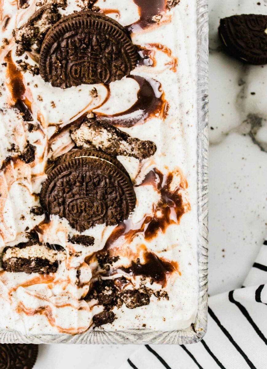 Oreo ice cream is topped with crushed Oreo cookies and a drizzle of hot fudge. 