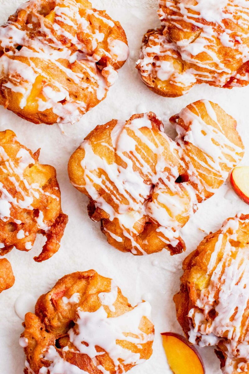 Multiple peach fritters are drizzled with icing. 