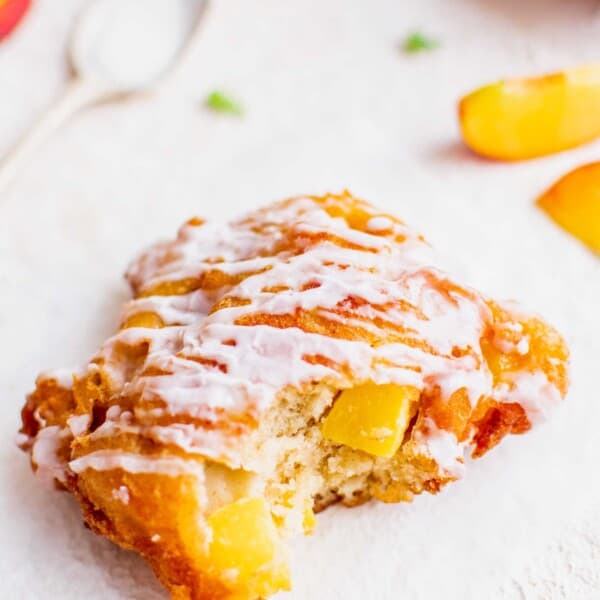 A peach fritter has been bitten into.