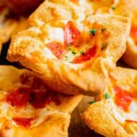 a pepperoni pizza muffin is stacked on top of several other pizza muffins garnished with fresh parsley