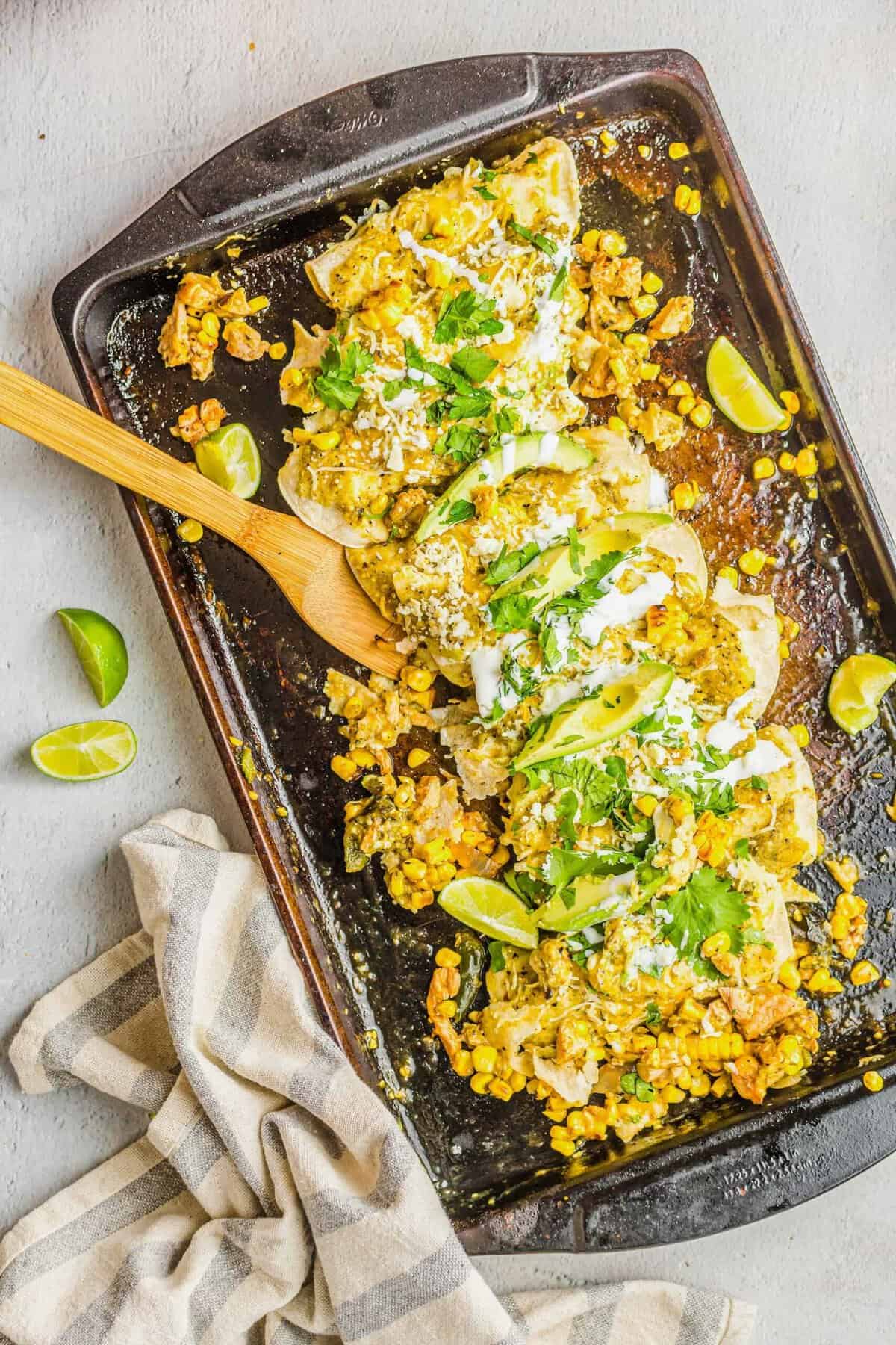 Sheet pan enchiladas are topped with cilantro, avocado slices, and sour cream. 