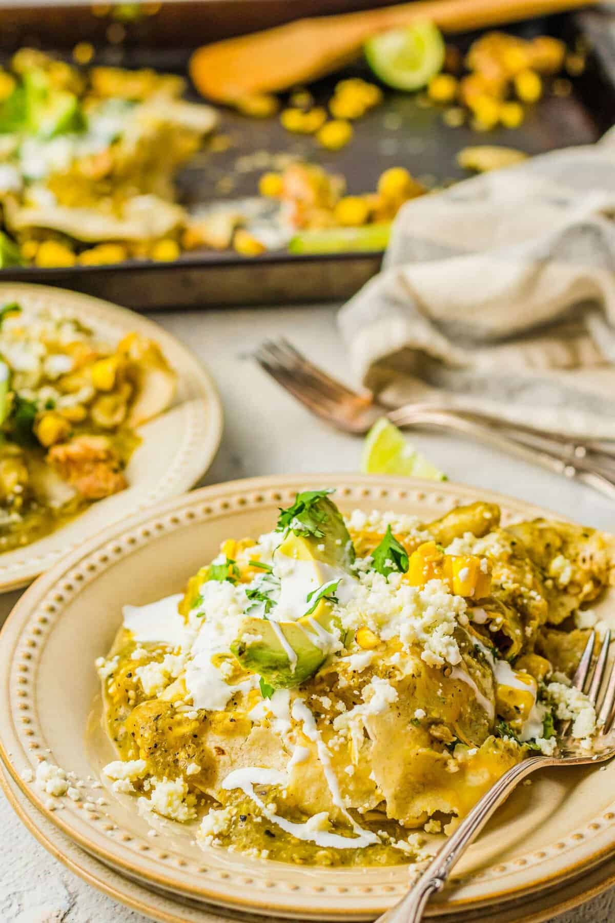 A fork is placed on a plate filled with garnished enchiladas. 