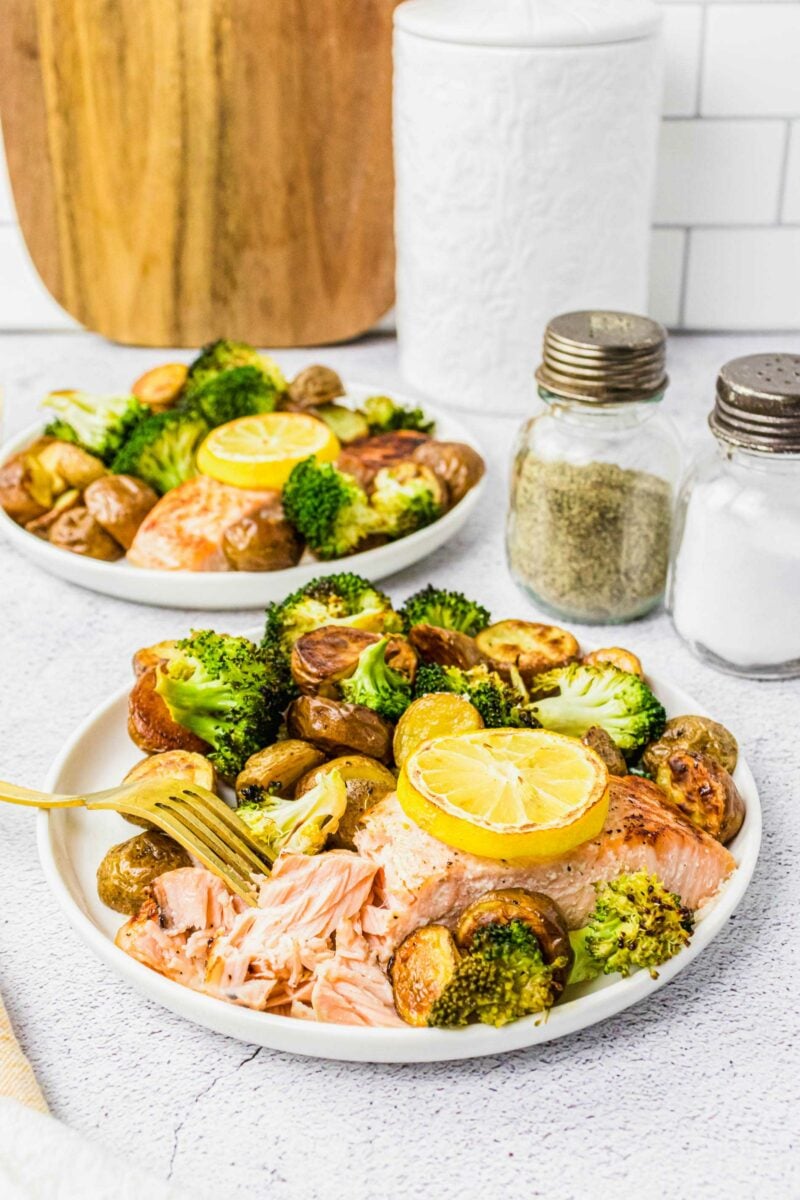 A salmon filet is being shredded by a fork, revealing perfectly cooked pink flaky meat. 