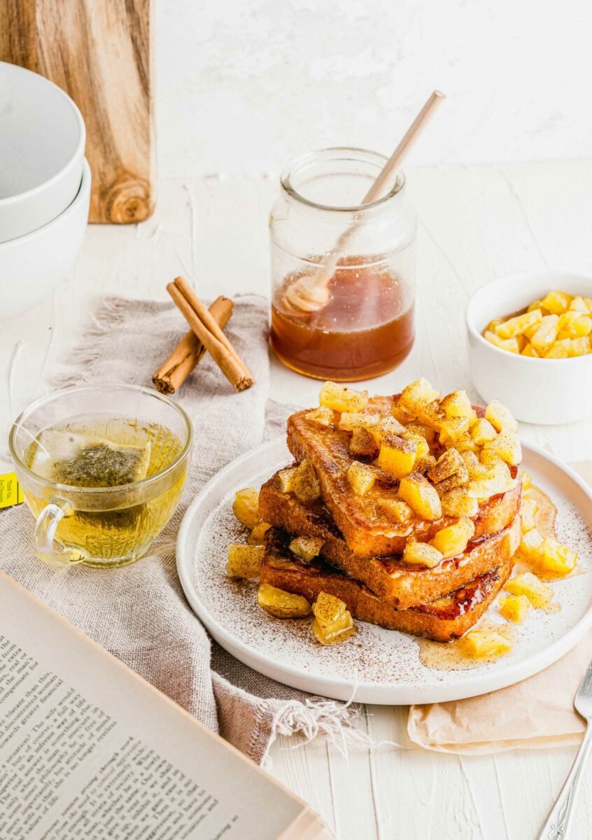 A stack of French toast is topped with caramelized apples. 