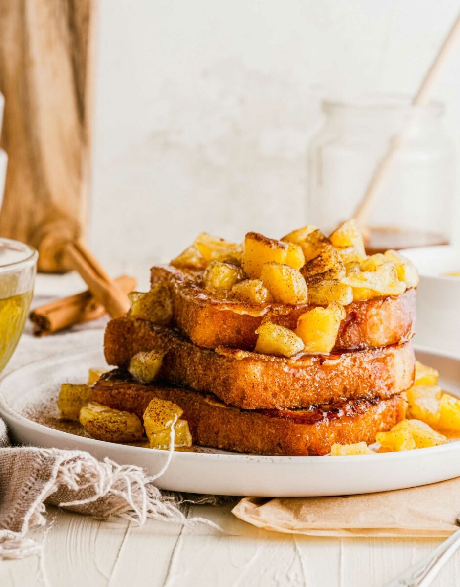 Three pieces of French toast are topped with apples. 