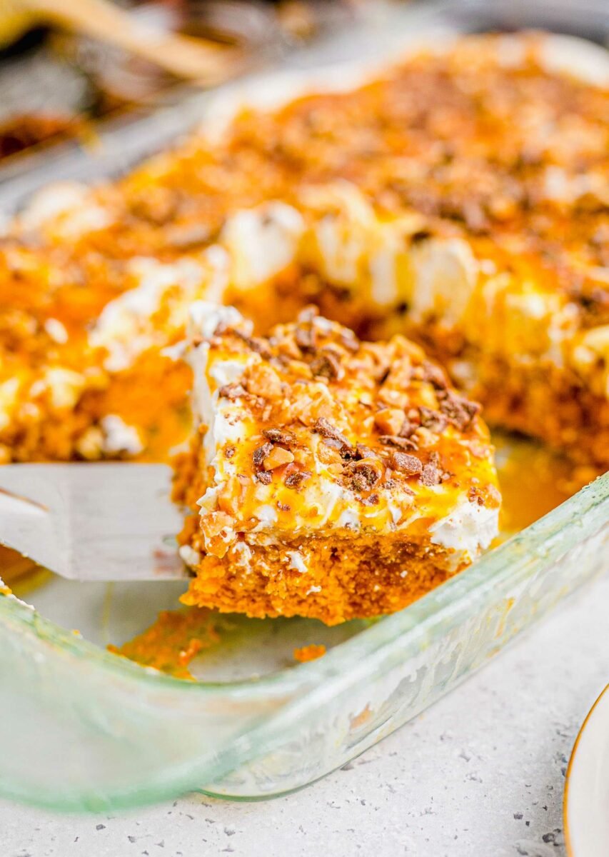 A piece of cake is being lifted from the glass baking dish. 