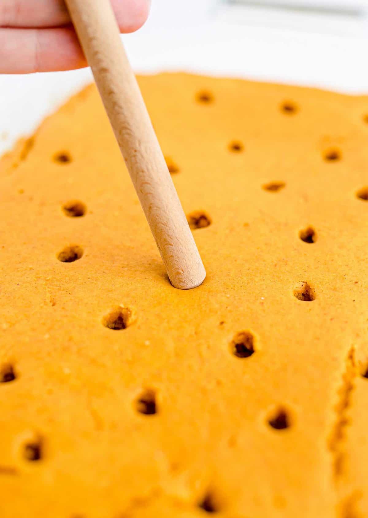 Poking holes into pumpkin cake