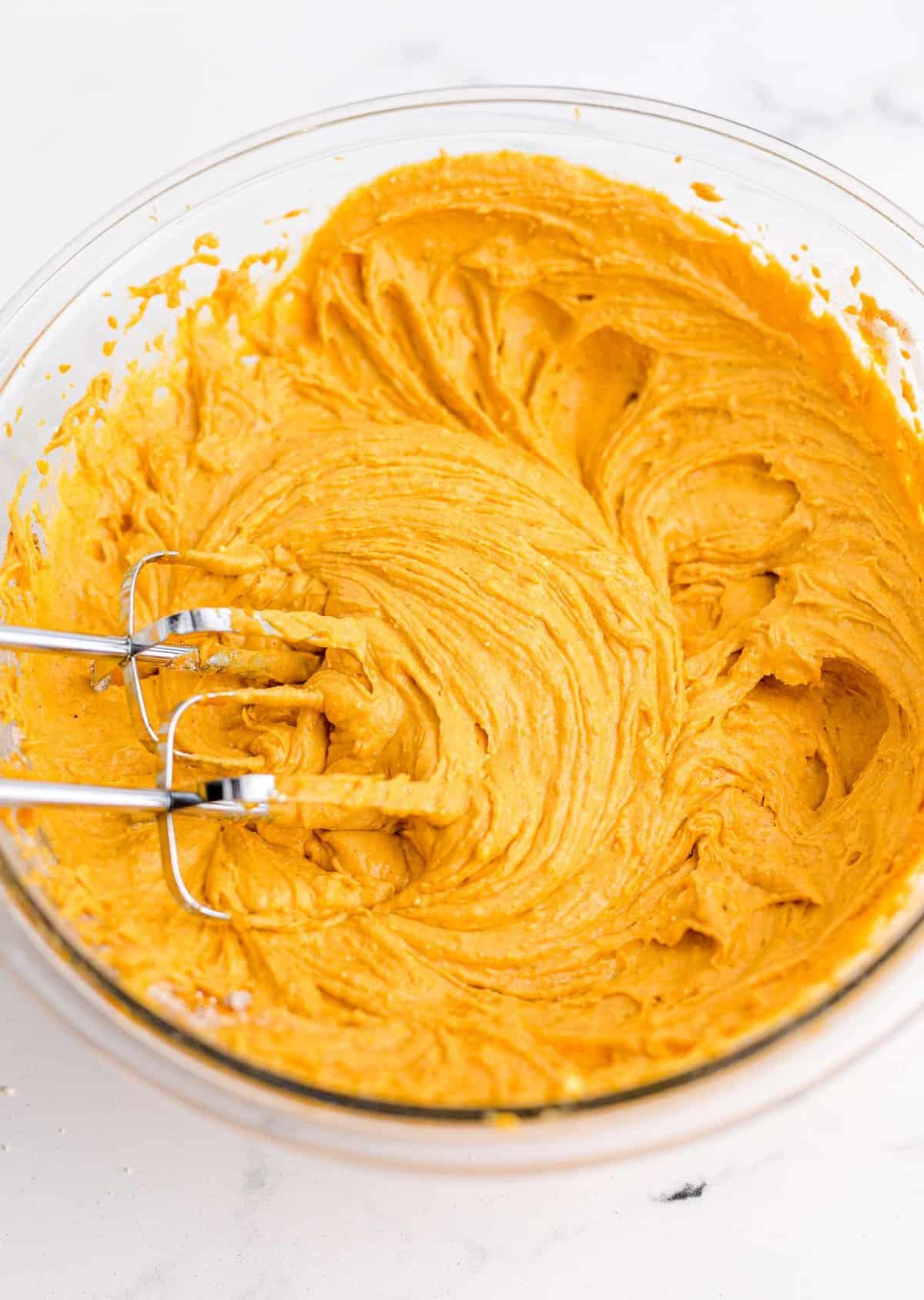 Pumpkin cake batter in a glass bowl with a whisk