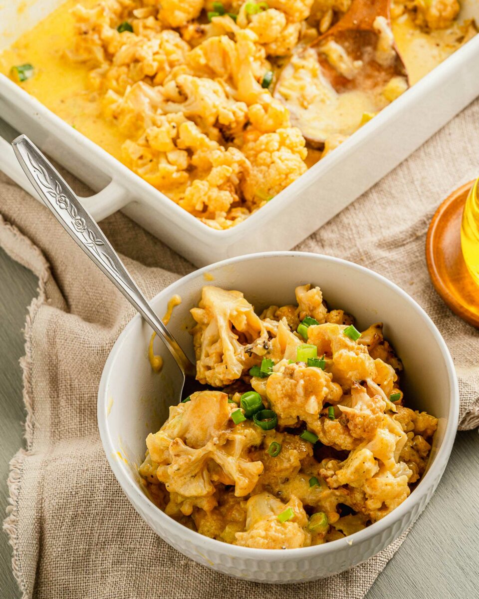 A bowl is filled with a personal serving of cheesy cauliflower. 