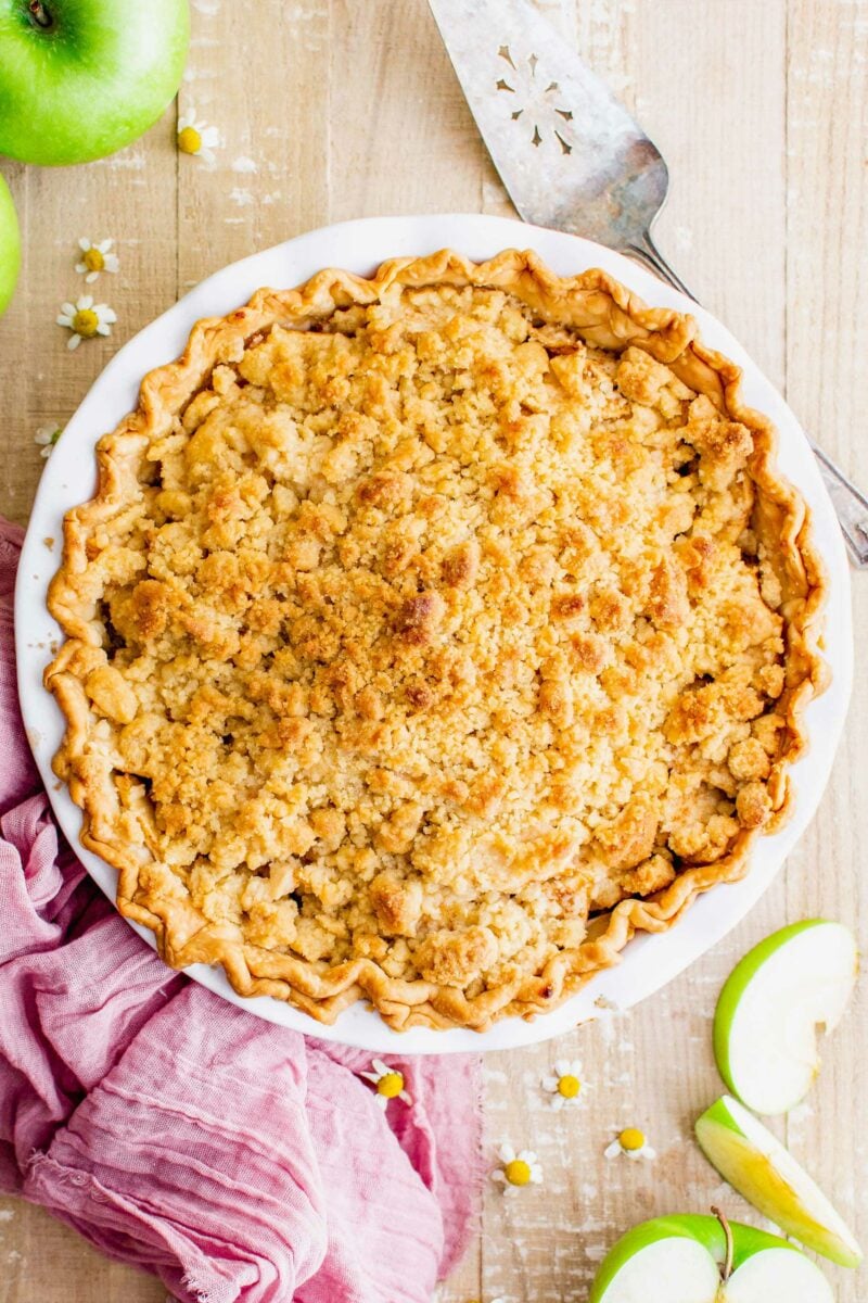 A dutch apple pie is presented in a white baking dish.