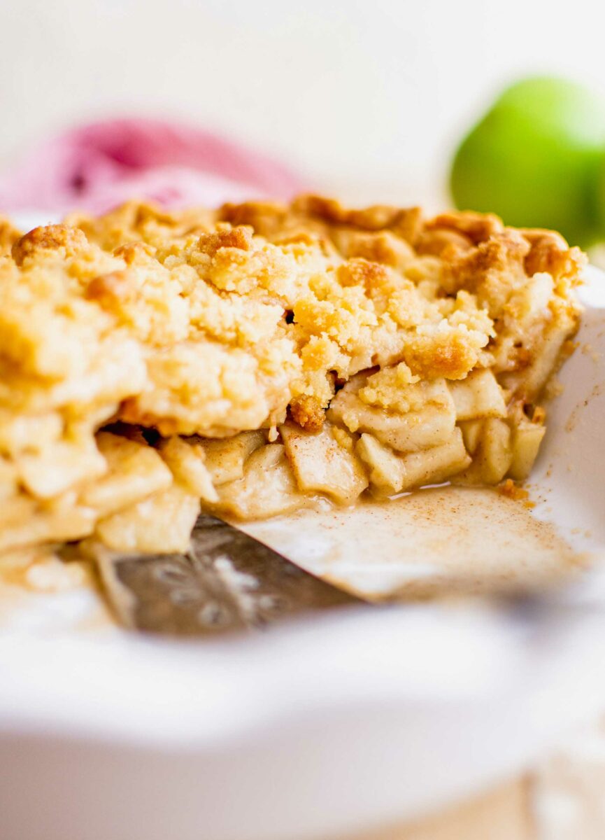 A slice of apple pie has been removed, showing the perfectly cooked apple pie filling in the center of the pie. 