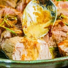 Glaze is being drizzled atop a serving of sliced pork tenderloin.