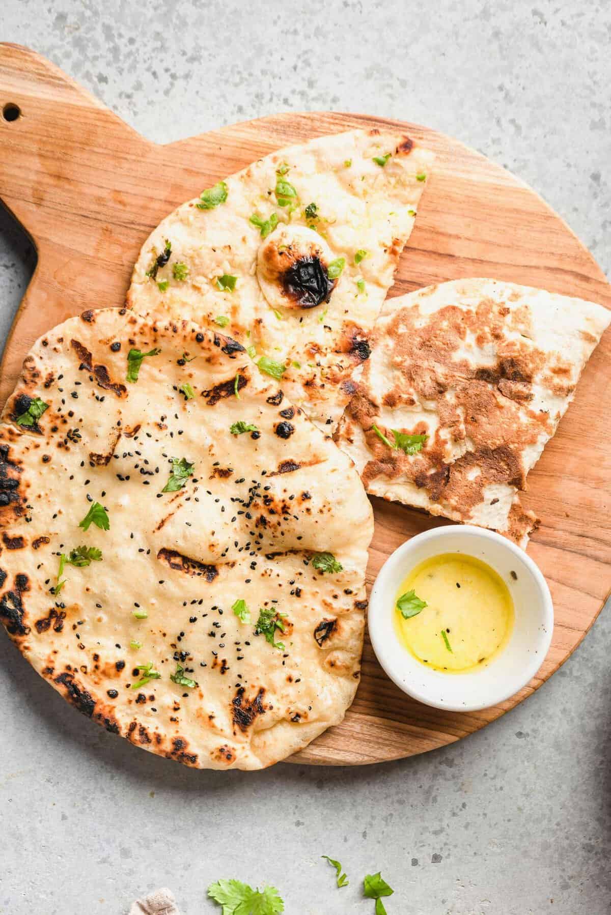 Naan is presented on a wooden cutting board. 