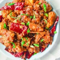 Cooked chicken is topped with peppers and green onions.