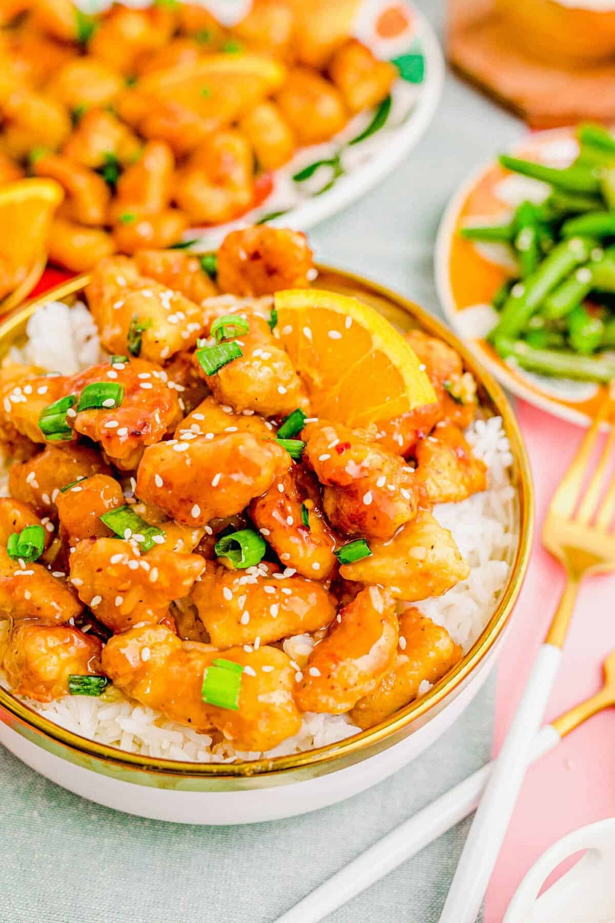 A bowl of orange chicken over white rice