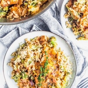 Two plates and a skillet of cheesy broccoli, rice, and chicken