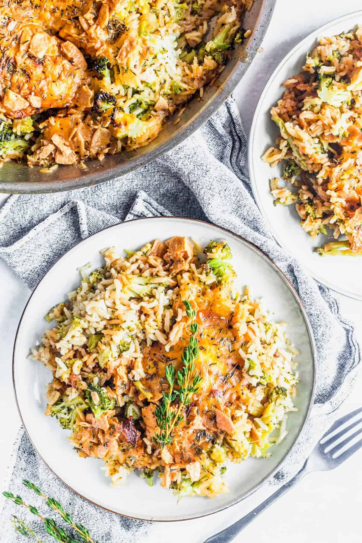 Two plates and a skillet of cheesy broccoli, rice, and chicken