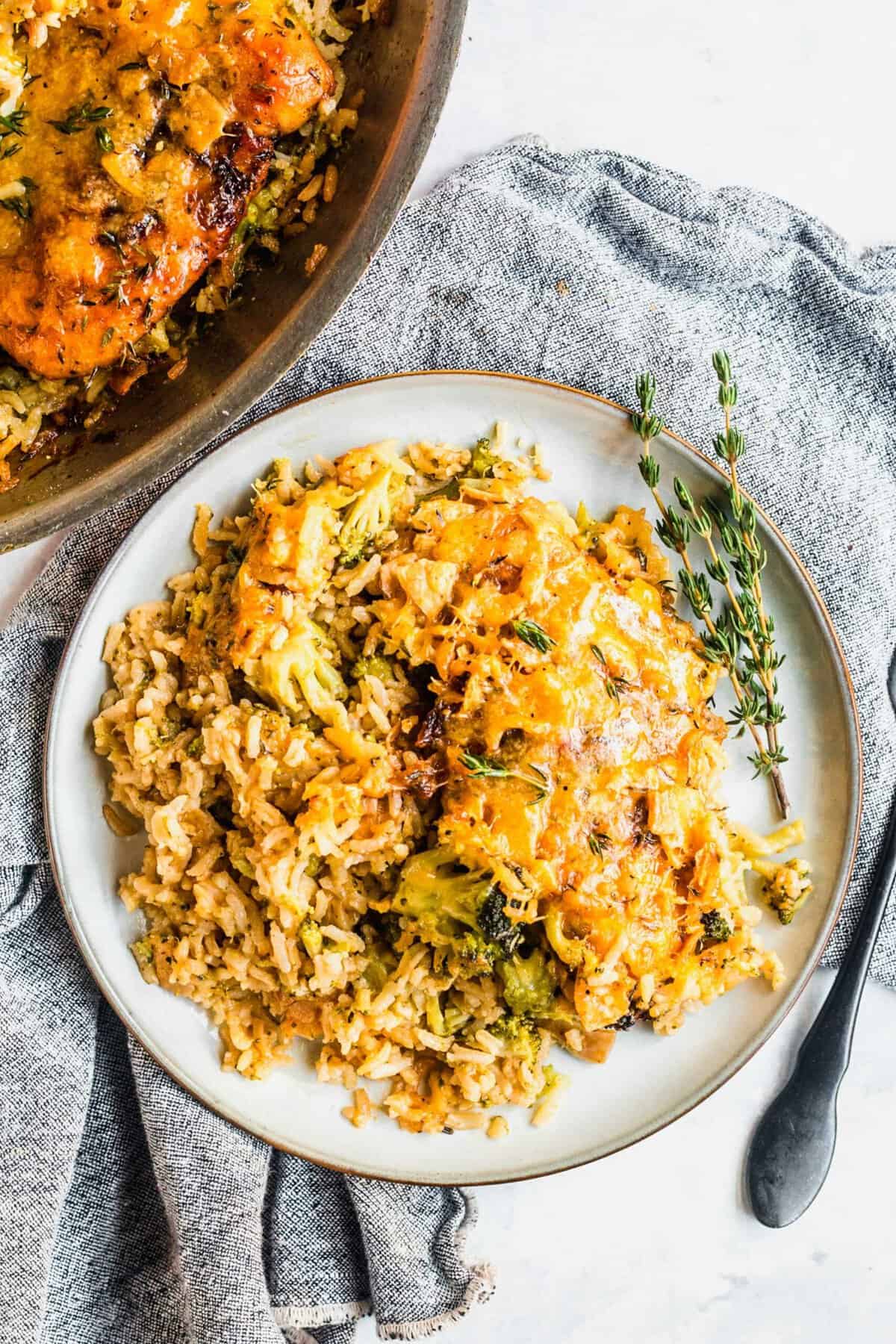 Cheesy broccoli rice and chicken on plate with sprigs of fresh thyme