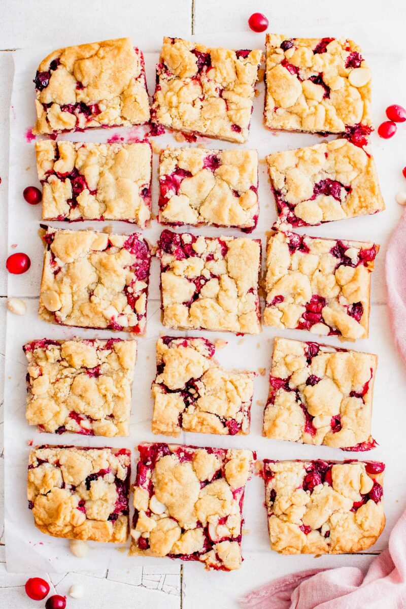 Shortbread bars have been sliced into multiple pieces on a sheet of parchment paper.