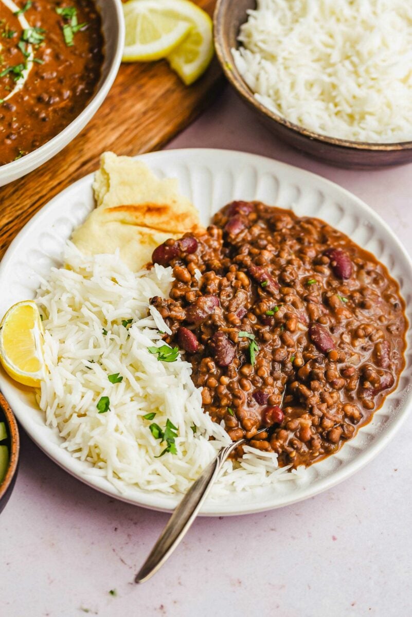 Rice, dal makhani, and naan are placed on a white plate. 