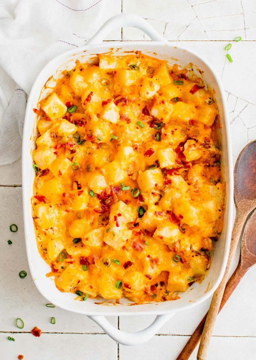 Baked potato casserole is topped with bacon bits and sliced green onions. 