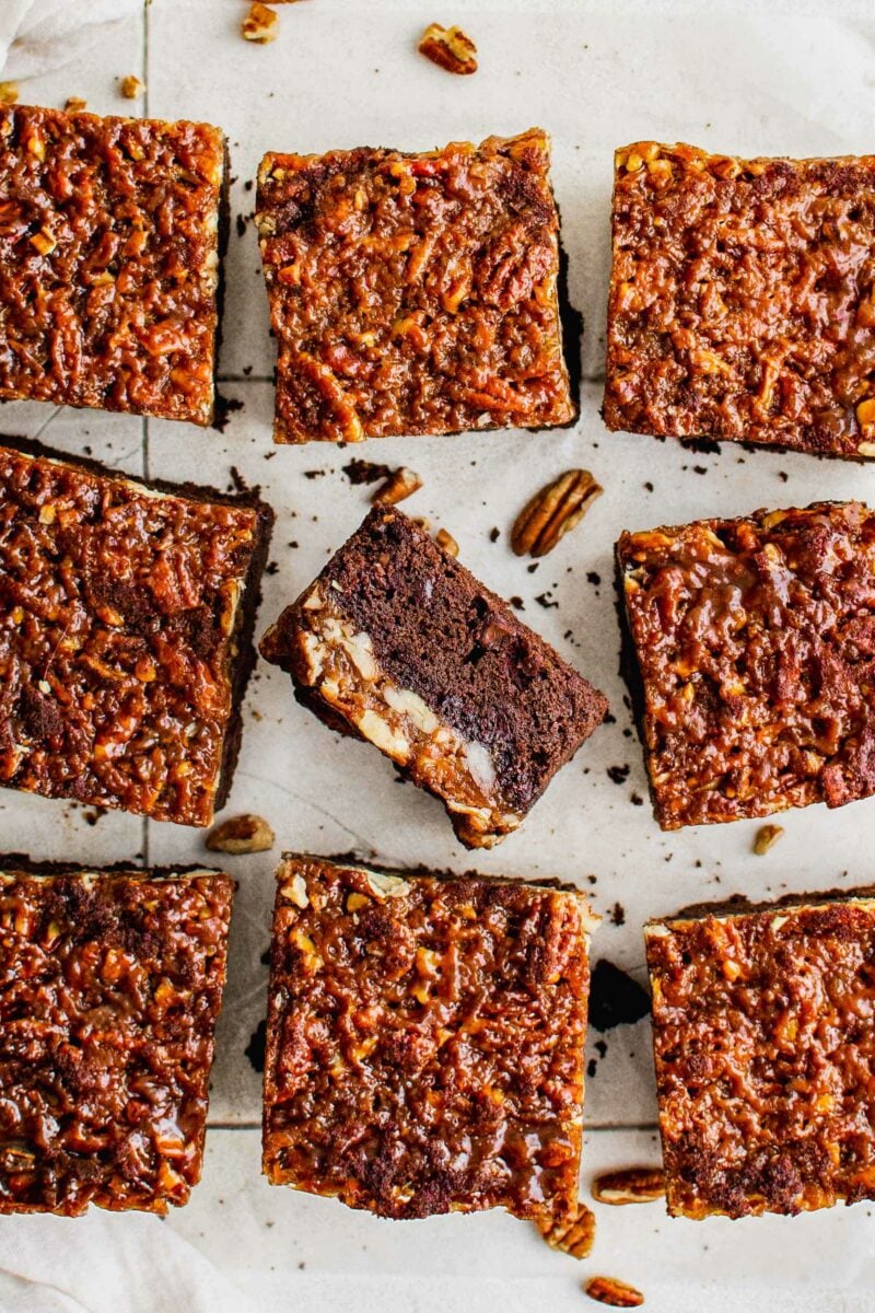 A few slices of pecan pie brownies are placed on a white surface. 