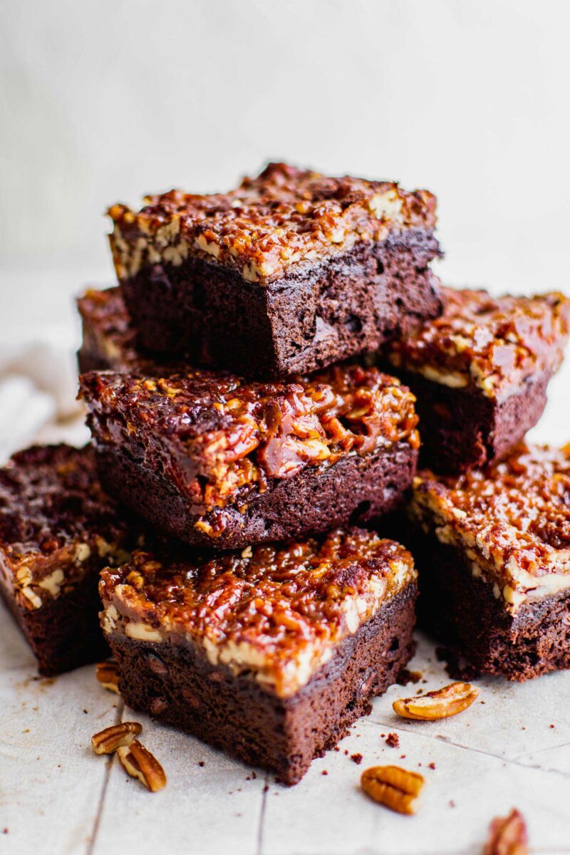 Multiple pecan pie brownies are stacked on top of one another in a big pile. 