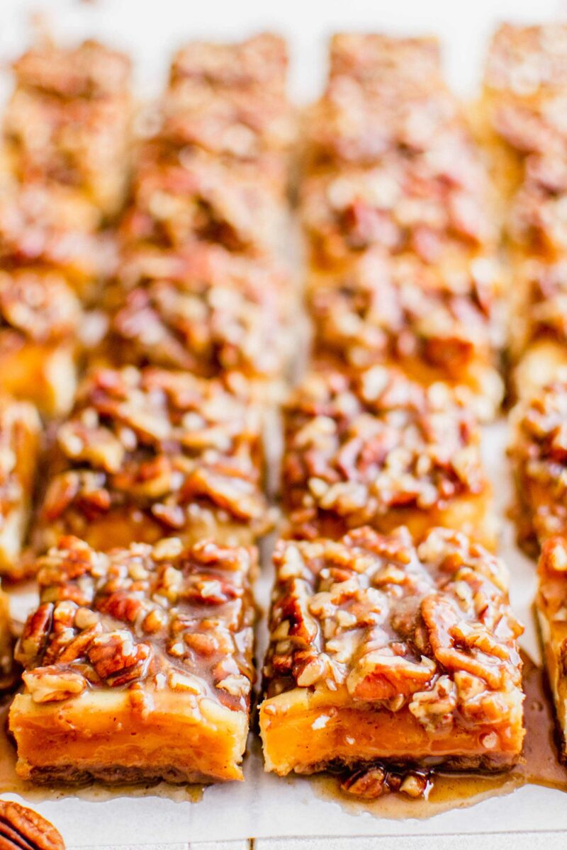Multiple cheesecake bars are topped with gooey pecan topping.