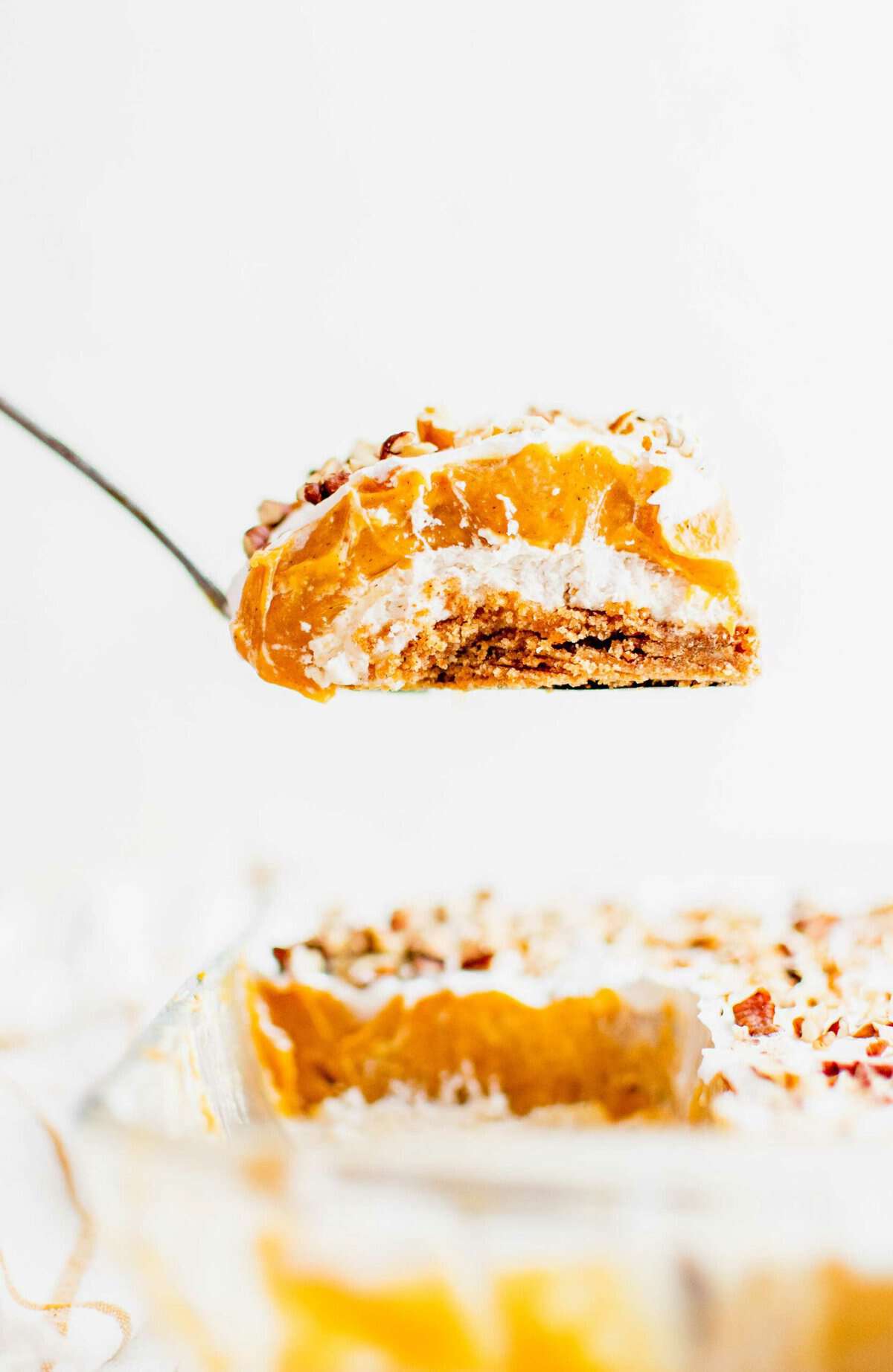 A small serving of pumpkin lush is being lifted from the baking dish,