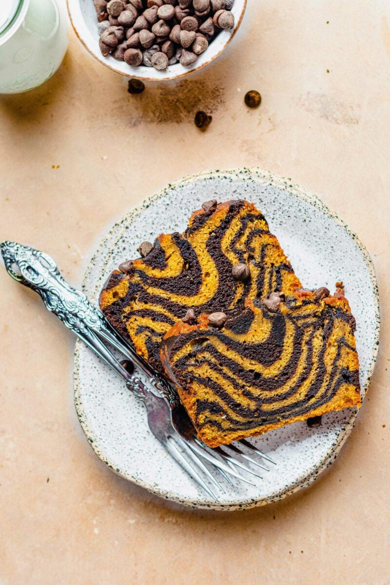 Two forks are placed next to two pieces of pumpkin chocolate bread. 