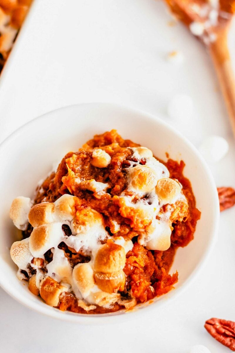 Gooey baked marshmallows top a serving of vibrant orange sweet potato casserole. 