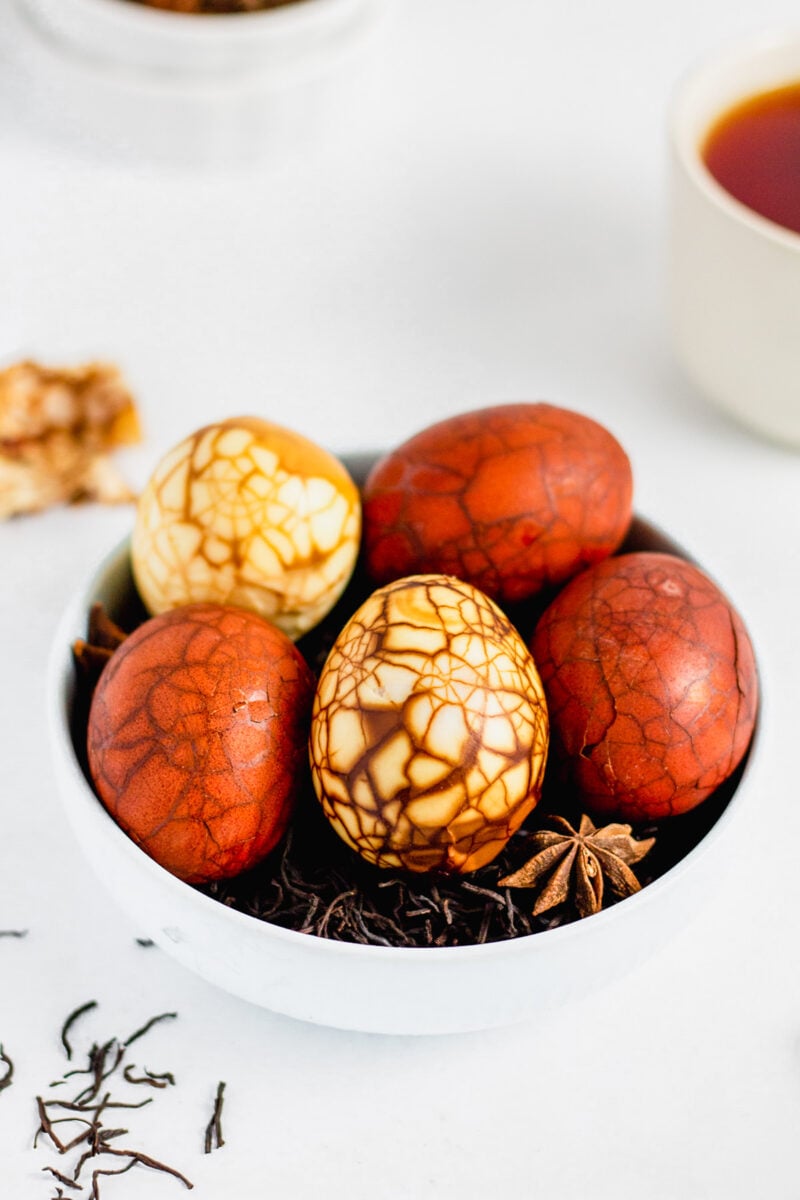 Marbled Taiwanese tea eggs on a bed of loose black tea in a white bowl