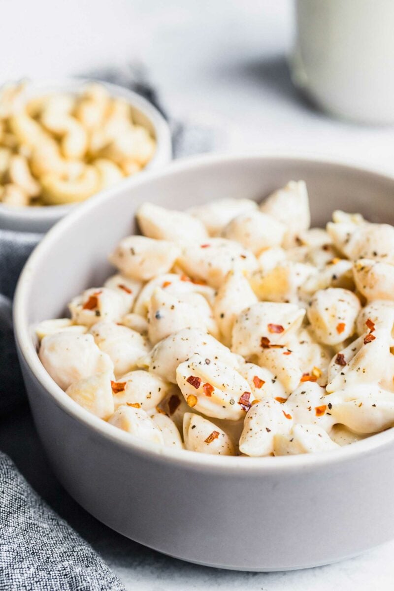 A round white bowl is filled with seasoned pasta. 