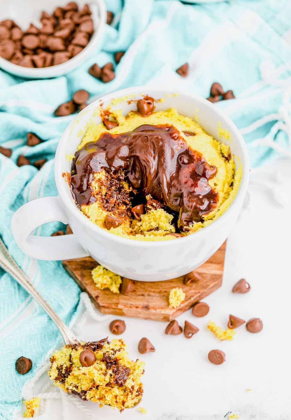 Chocolate chip cake in mug, pictured with spoon full of cake in foreground