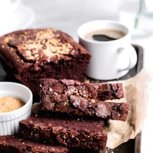 Slices of chocolate cinnamon bread on parchment-lined baking sheet with mug of coffee