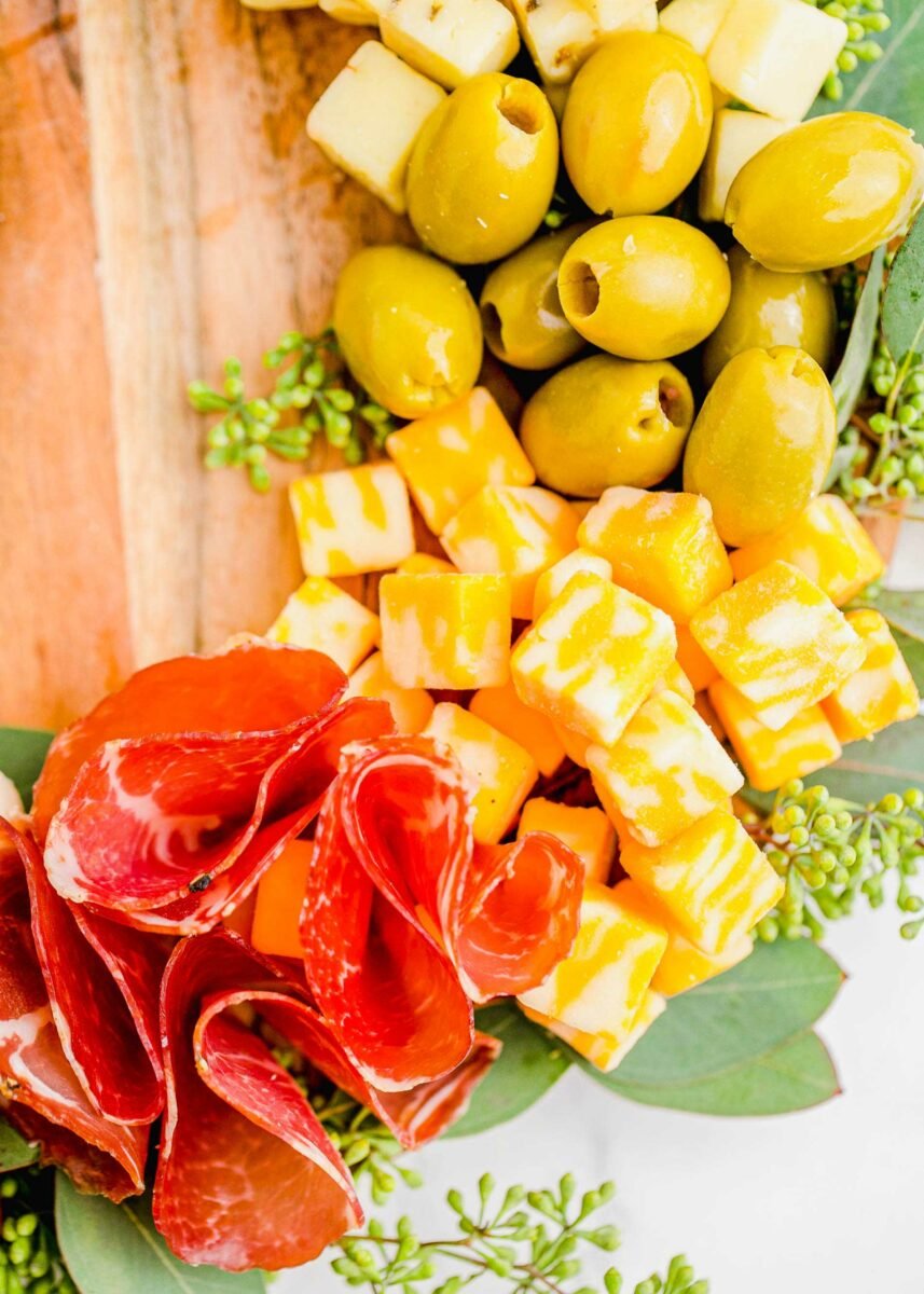 Eucalyptus leaves are placed in a circle around a filled wooden cutting board. 