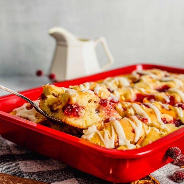 A slice of breakfast cake is being lifted out of a red baking dish.