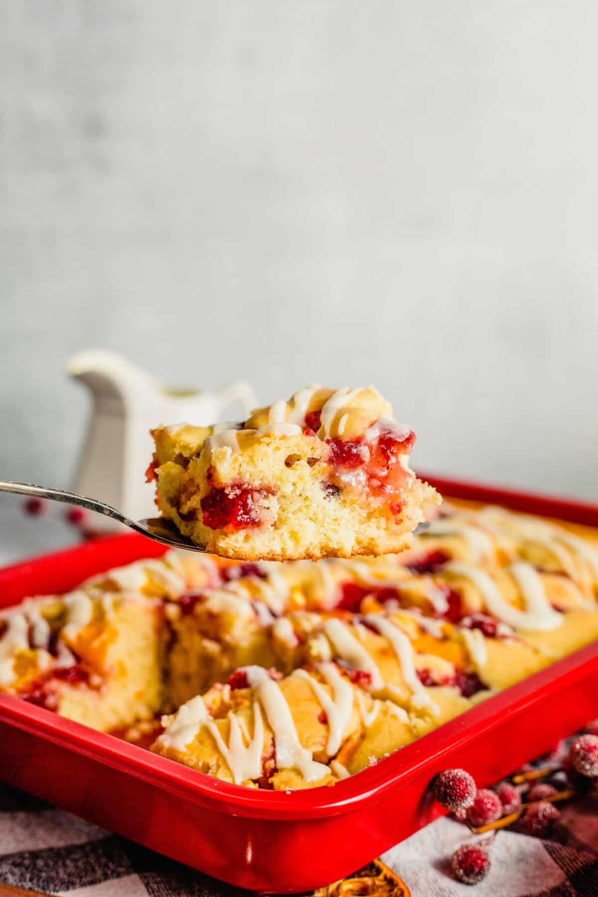 A slice of cake is being lifted from the full red baking dish.