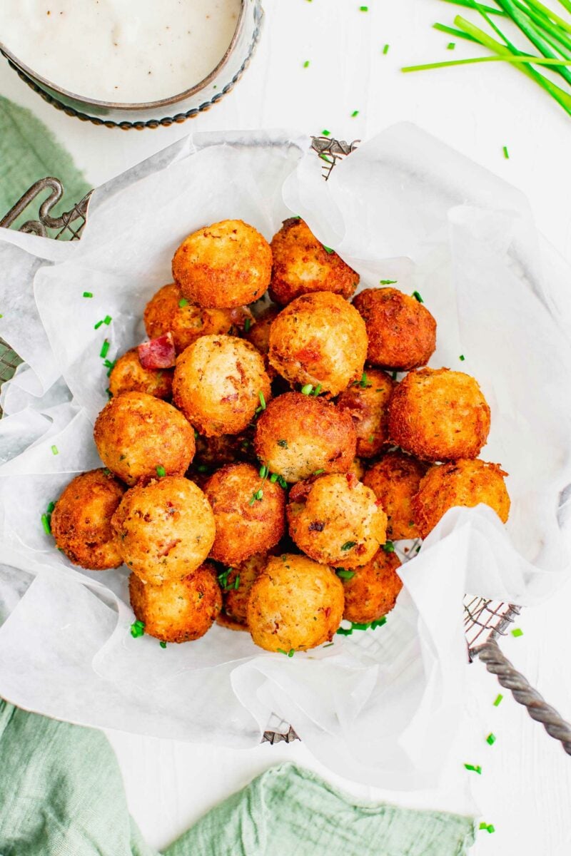 A basket of fried mashed potato balls is presented by a green tea cloth.