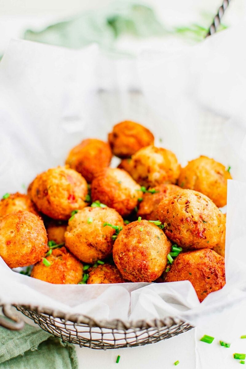 Mashed potato balls are in a pile and garnished with chives.